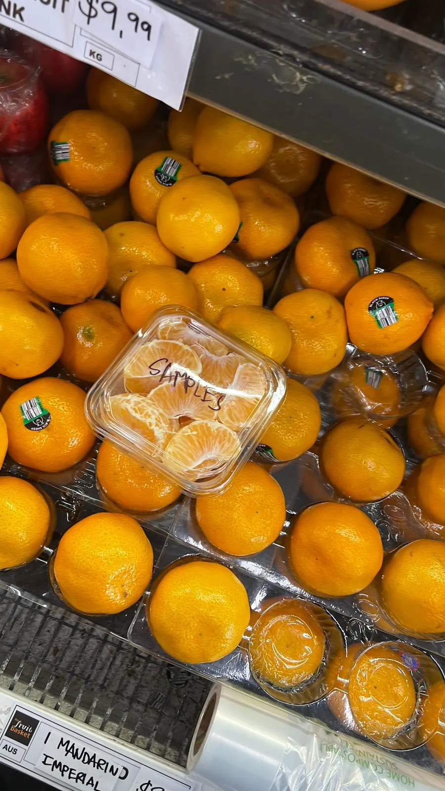 Fresh mandarins with sample segments and preserved fruit jars on the bench