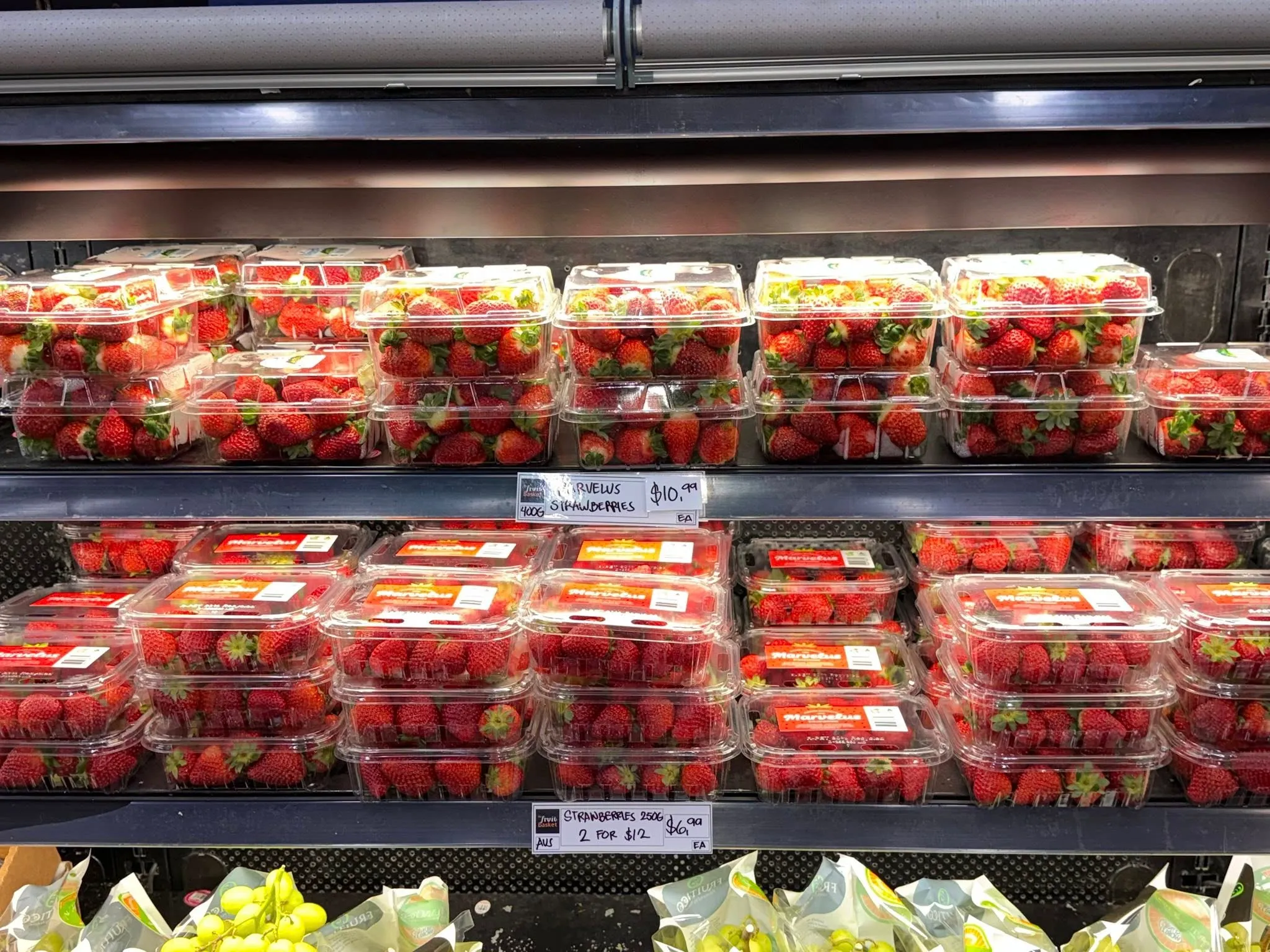 Trays of fresh strawberries in the refrigerated display case